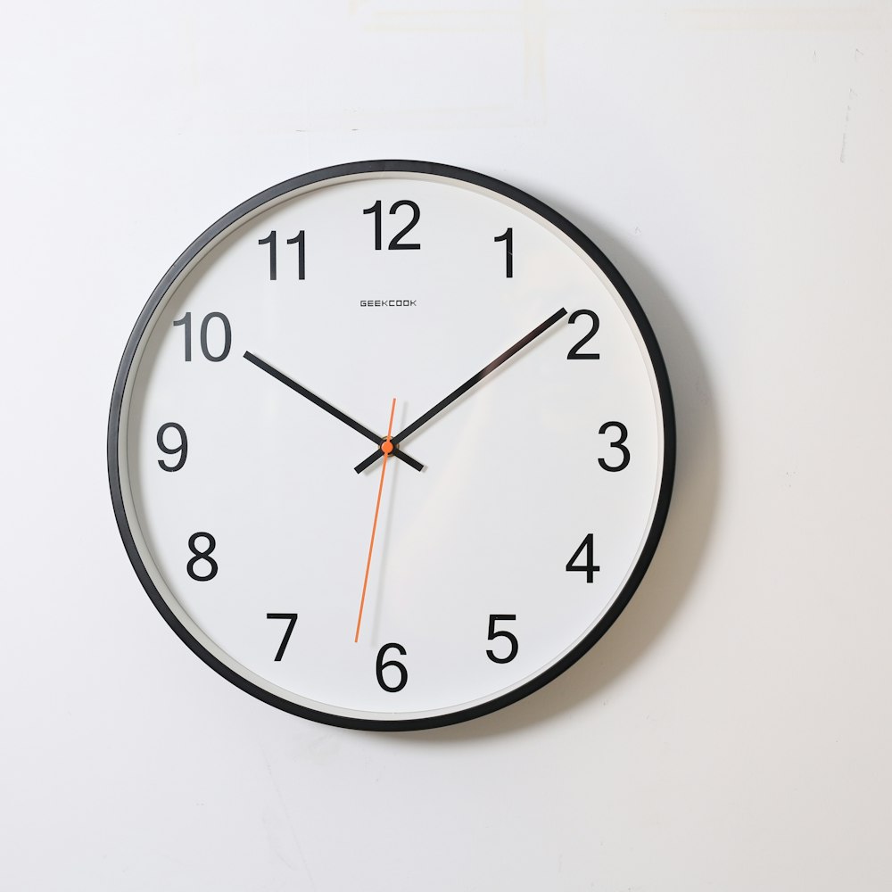 Round analogue wall clock showing ten past ten