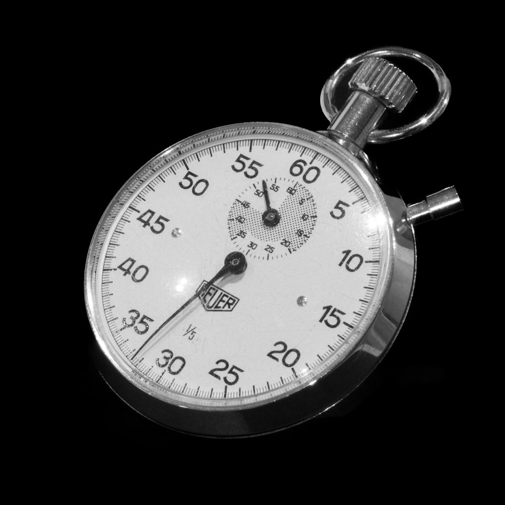 A close-up of a stopwatch on a black background