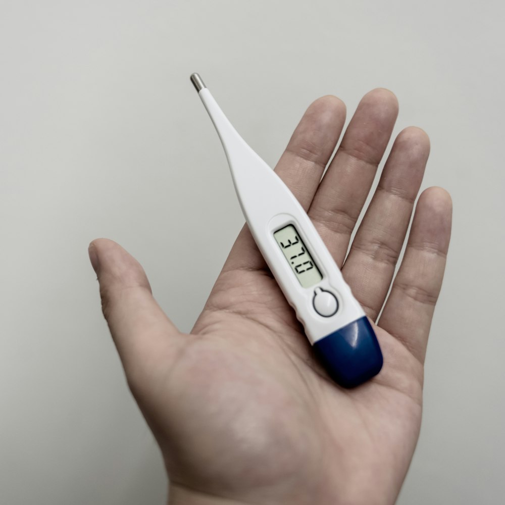 White and blue digital thermometer reading 36.9