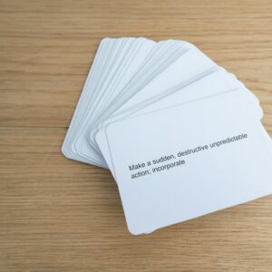 A stack of white cards with text on a light wooden surface
