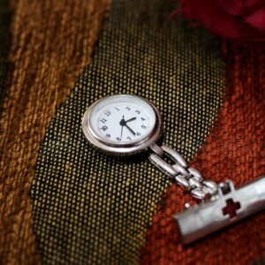 Silver pocket watch on brown fabric