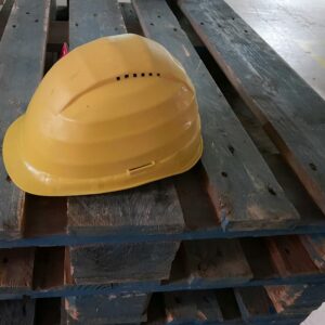 A yellow hard hat resting on a wooden pallet