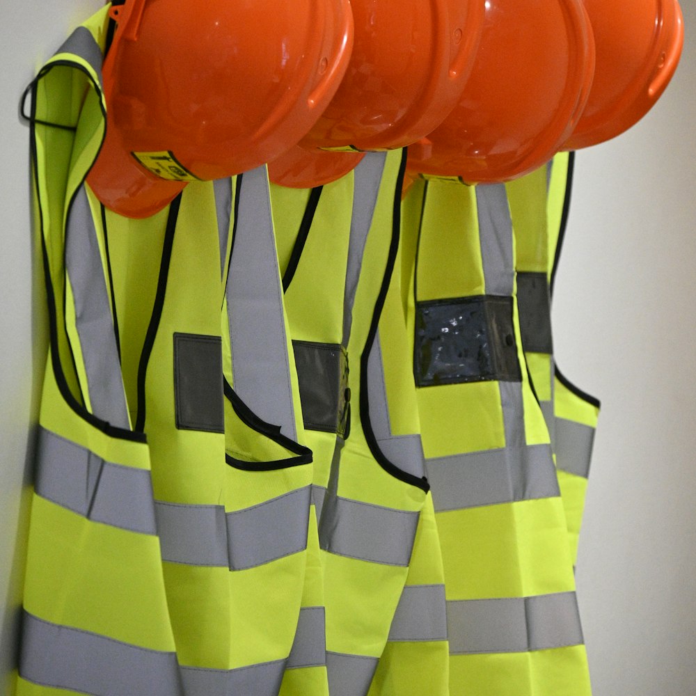 Orange hard hats and neon yellow safety vests hanging on a wall