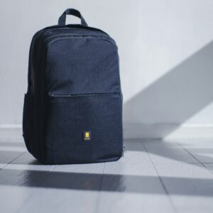 Black backpack with a small yellow logo on a white floor