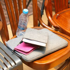A grey laptop sleeve, notebook and pink purse on a wooden chair