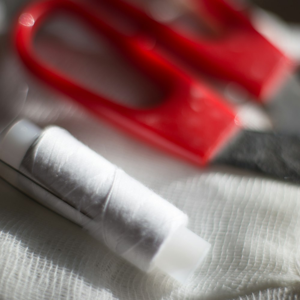 Red and black handled scissors on white fabric