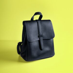 A black leather backpack on a yellow background