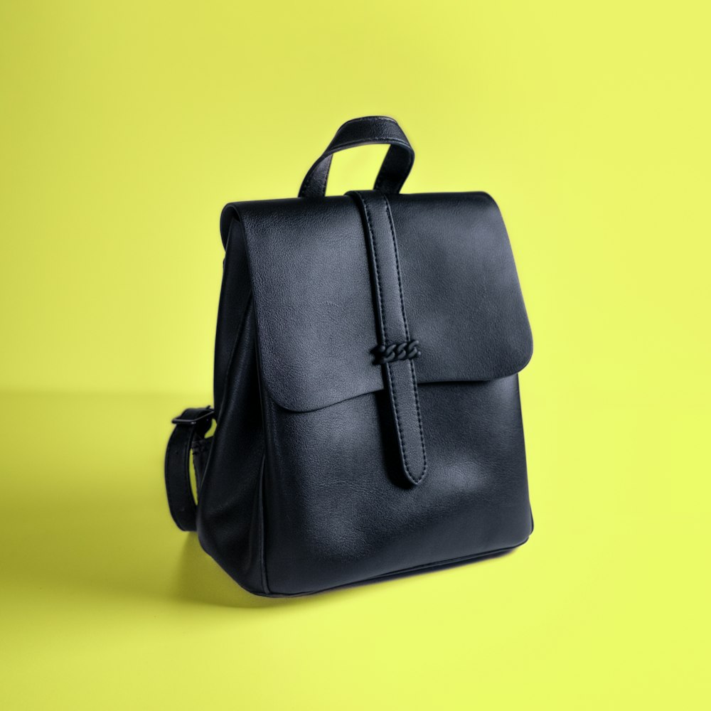 A black leather backpack on a yellow background