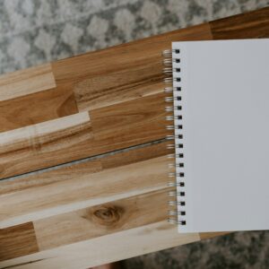 A white spiral notebook on a wooden table