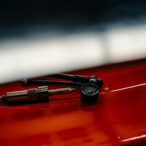 A tyre pressure gauge and inflator on a red surface